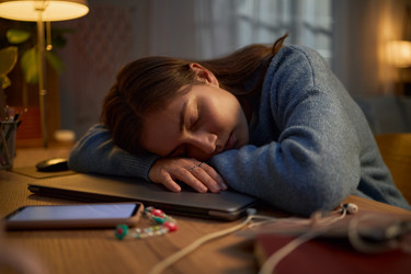 Измученная женщина спит на ноутбуке за рабочим столом во время удаленной работы - SeventyFour