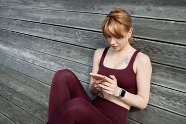 Спортивная женщина, отслеживающая ход тренировки на смартфоне на открытом воздухе - SeventyFour
