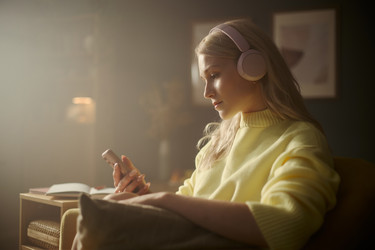 Женщина в наушниках использует смартфон для цифровых развлечений - DragonImagesAsia