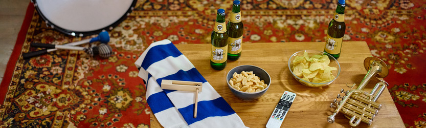 Пивные бутылки и закуски на столе, приготовленные для футбольных болельщиков, наблюдающих за игрой - SeventyFour