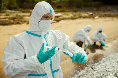 Мужчина-эколог в защитном костюме собирает пробы воды для проверки на загрязнение - DragonImagesAsia
