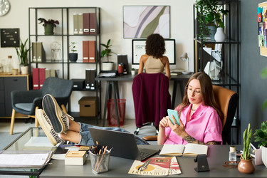 Женщина-дизайнер, использующая смартфон в студии Creative Office - Mediaphotos