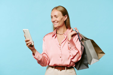 Женщина с сумками для покупок и смартфоном в руках на распродаже в Черную пятницу - AnnaStills