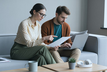Женщина и мужчина анализируют документы и работают на ноутбуке - SeventyFour