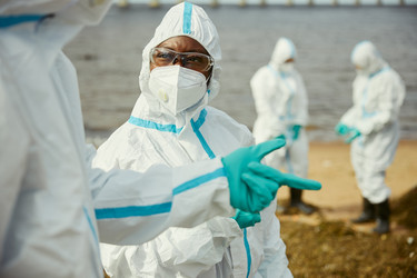 Чернокожая женщина-эколог в защитном костюме изучает загрязнение воды - DragonImagesAsia