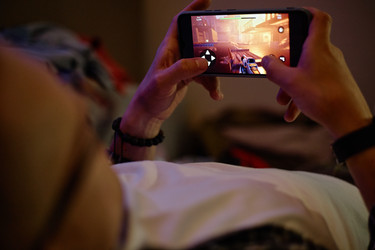 Мужчина ночью играет в мобильную онлайн-видеоигру на смартфоне - SeventyFour