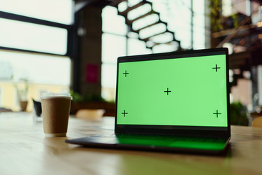 Ноутбук с зеленым экраном на столе для макета удаленной работы - DragonImagesAsia