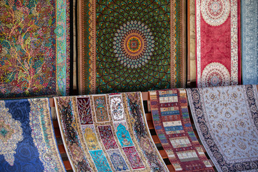 красочные гобелены демонстрируют замысловатые узоры на рынке в оживленном городе солнечным днем - aspsvz