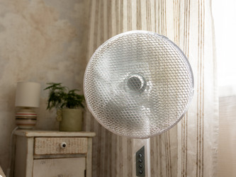 стоящий металлический вентилятор у ближнего окна. теплый, простой домашний интерьер с умиротворяющей летней атмосферой - MyJule