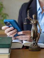адвокат набирает сообщение на смартфоне возле статуи богини правосудия. онлайн-консультация - MyJule