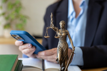Адвокат набирает сообщение на смартфоне возле статуи богини правосудия. Онлайн-консультация - MyJule