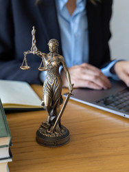 адвокат печатает на ноутбуке возле статуи богини правосудия. онлайн-консультации. фотография высокого качества - MyJule