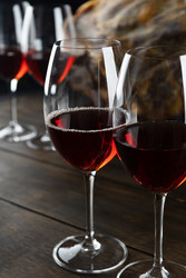 красное вино в хрустальных бокалах. нарезанная ломтиками ветчина на темном дереве. изысканное сочетание. темный угрюмый фон. испанский деликатес - RusAKphoto