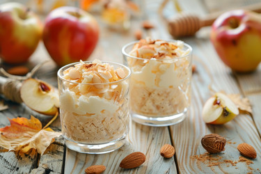 вкусный яблочный десерт со взбитыми сливками, миндалем и корицей на деревянном столе - yliv