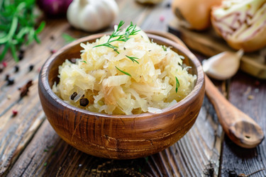квашеная капуста с укропом и специями в деревянной миске на деревенском столе - yliv