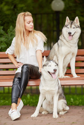 Young blond woman with two dogs Husky sits on - paha_l