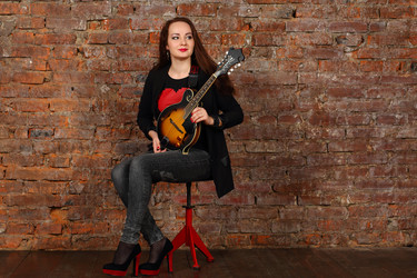 Pretty young woman with mini guitar sits on stool - paha_l