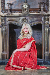 Blonde woman in red dress sits at fireplace in - paha_l