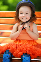 Cute little girl in blue helmet sits on bench at - paha_l
