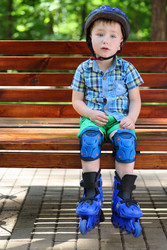 Little handsome boy in roller-blades sits in bench - paha_l