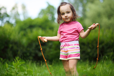 Little cute girl poses with skipping rope in - paha_l