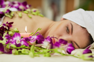 Woman lies on couch among flowers and looks at - paha_l