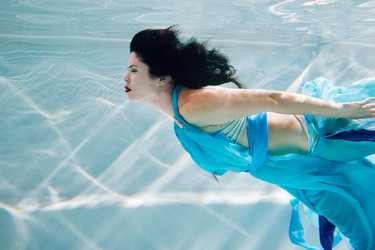 Young black-haired woman in blue dress swims - paha_l
