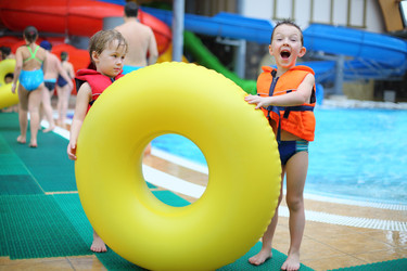 Two little boys in a life jacket near a big yellow - paha_l
