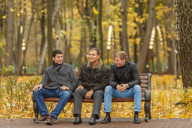 Three young men in black outerwear sitting on park - paha_l