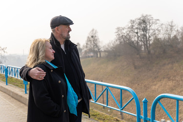 зрелая пара обнимается у синих перил на открытом воздухе - AliakseiSmalenski