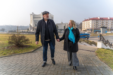 зрелая пара держится за руки и прогуливается по городу - AliakseiSmalenski