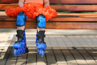 Legs of little girl in roller skates sitting on - paha_l