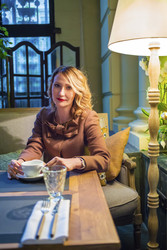 Middleaged blonde woman sits with tea and looks at - paha_l