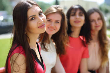 Four young cute women sit on bench outdoor at - paha_l