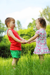 Little girl and boy hold hands on fresh green - paha_l