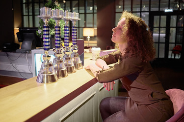 Young curly woman sits at bar counter in evening - paha_l