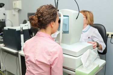 Doctor looking patients eye with an instrument - paha_l
