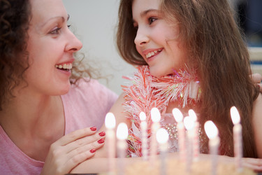 Smiling mother and daughter with birthday cake and - paha_l