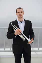 Man in black suit poses with trumpet on roof of - paha_l