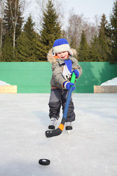 Happy little boy on skates with a hockey stick and - paha_l