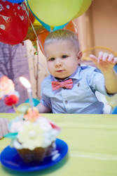 Little boy sits at birthday table with cake and - paha_l