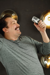 Smiling man with mustache poses with microphone in - paha_l