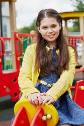 Smiling girl sits at children playground on summer - paha_l