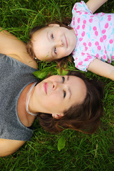 Little cute girl and her mother lie on grass and - paha_l