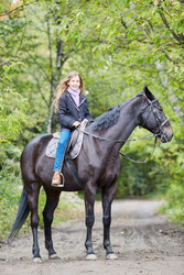 Smiling teenage girl sits on chestnut horse in - paha_l