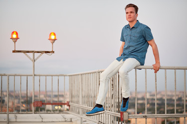 Young man in denim clothes sits on the fencing of - paha_l