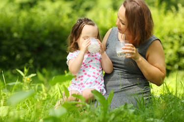 Little girl drinks milk and her mother looks at - paha_l