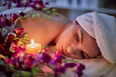 Woman lies on couch with flowers lit by burning - paha_l
