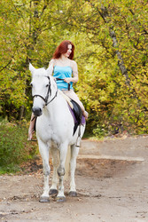 Young smiling red-haired woman rides on white - paha_l