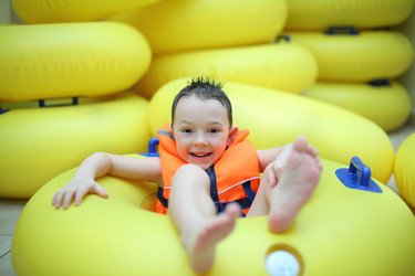 Happy little boy in a life jacket sitting in a big - paha_l